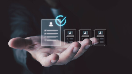 A person's hand is extended forward, displaying a series of glowing digital profiles and checklists, with one prominently selected.