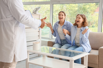 Obraz premium Happy lesbian couple visiting fertility doctor after IVF in clinic