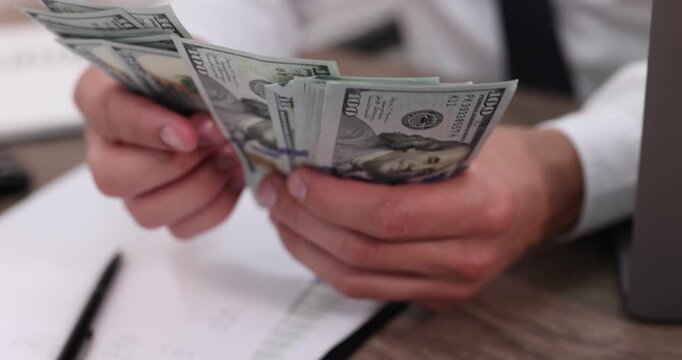 Man counting dollar banknotes at table, closeup
