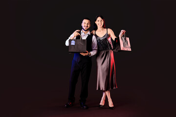 Young couple with shopping bags on dark background. Cyber Monday