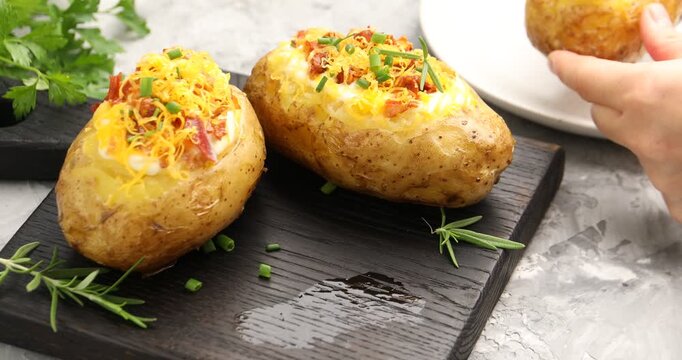 Woman taking tasty stuffed baked potato at grey table, closeup