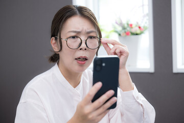 A woman in her 40s looking at her smartphone. “Could it be presbyopia?” An image of her looking...