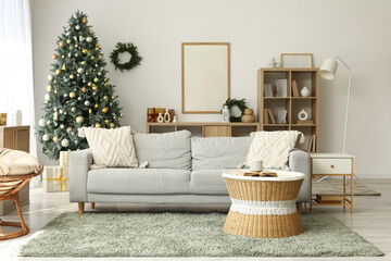 Interior of light living room with sofa, bookshelf and Christmas tree