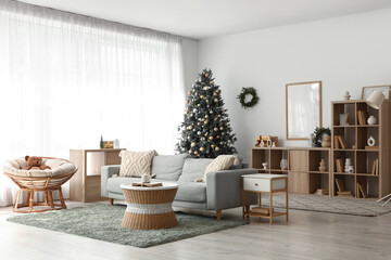 Interior of light living room with sofa, bookshelf and Christmas tree