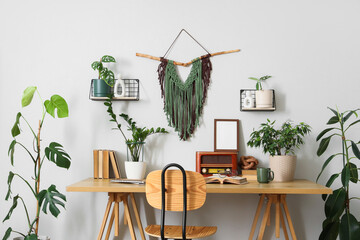 Interior of light office with workplace, books and houseplants