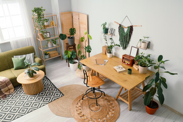 Interior of light office with workplace, folding screen and houseplants