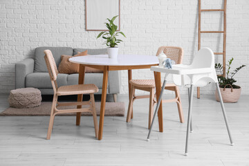 Interior of dining room with table, baby highchair and sofa