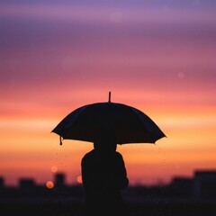 Silhouette of Person with Umbrella at Sunset.