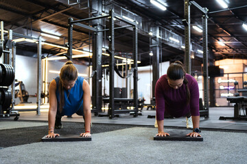 Two strong women are enhancing their upper body and core strength by performing push-ups on balance pads, adding an element of instability to their fitness workout