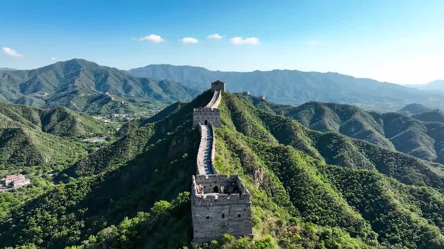 The Great Wall of China winding through lush green mountains under a clear blue sky.