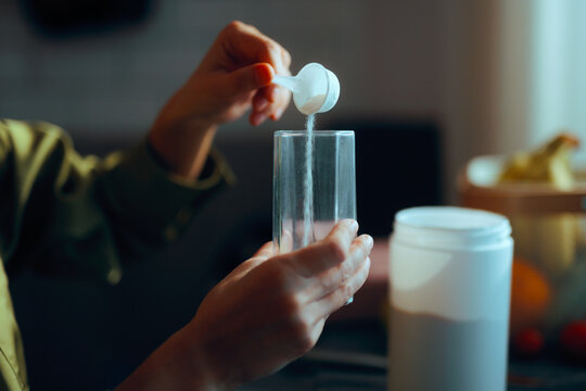 Person Pours a Spoonful of Collagen into a Glass to Prepare the Drink. Woman taking nutritional supplement for beauty and health 
