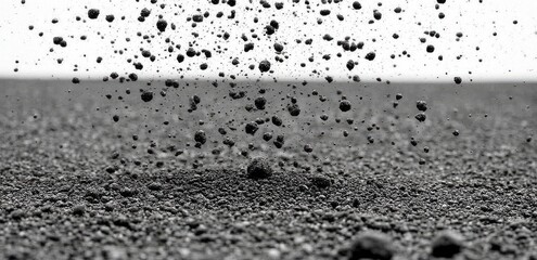 Small, dark particles raining down on a dark surface