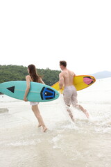 Fototapeta premium Couple lover running on beach with surfboards, splashing water and smiling under summer sunlight, concept of friendship, vacation, holidays, surfing, freedom, and fun tropical lifestyle. 