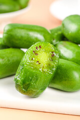 Fresh Green Mini Kiwi Fruits with Soft Heart-Shaped Seeds on White Plate