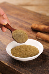 Ground Cumin Spice Powder in Wooden Spoon - Essential Cooking Ingredient on Rustic Wood Background