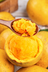 Fresh Pumpkin Puree on Wooden Spoon with Whole Pumpkins for Autumn Cooking