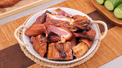 Chinese Roasted Duck Pieces with Crispy Skin and Cucumber Garnish on Wooden Table