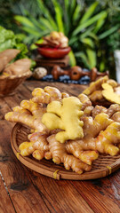 Fresh Yellow Ginger Root on Wooden Plate Against Tropical Plant Background