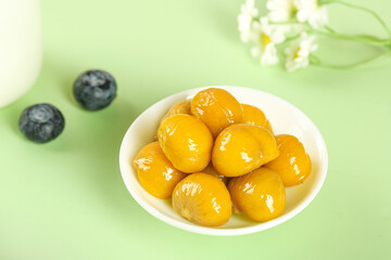 Fresh Cooked Chestnuts in Bowl with Blueberries on Green Background