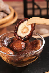 Fresh Shiitake Mushrooms in Glass Bowl Being Picked with Wooden Tongs for Cooking Preparation
