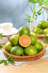 Fresh Yichang Qingxiang Honey Tangerines in Wicker Basket with Tea Cup on Wooden Table