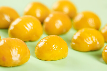 Golden Yellow Glossy Candies on Green Background - Sweet Confections Food Photography