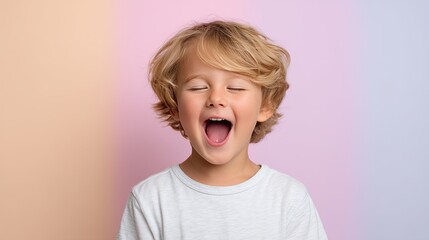 Closeup of little boy giggling uncontrollably, showcasing pure joy and happiness against soft pastel background. His playful expression captures essence of childhood delight