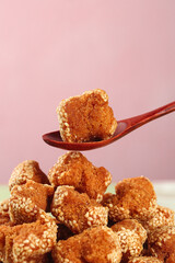 Traditional Guangxi Sesame Balls Chinese Dessert Specialty on Wooden Spoon Pink Background