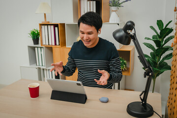 happy man using digital tablet and wireless earbuds making video call in home office
