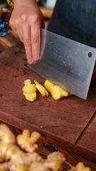 Freshly Dug Yunnan Mountain Ginger Root Being Chopped on Wooden Cutting Board - High Quality Organic Spice Preparation