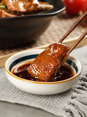 Braised Goose Piece with Chopsticks Over Sauce in Traditional Asian Cooking Setting