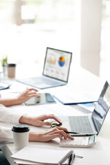 A professional is working at a modern office desk, typing on a laptop with documents and a coffee cup nearby. focused on business tasks, data analysis, and office productivity.
