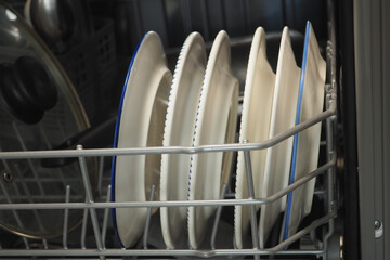 Clean plates stacked in a modern dishwasher after a meal