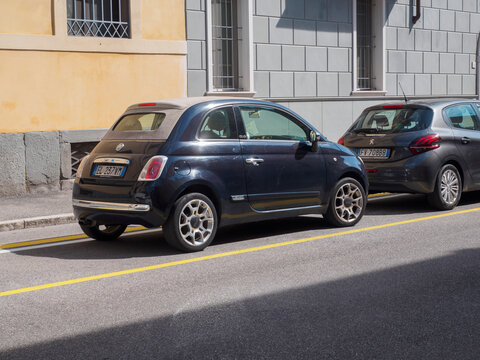 Fiat 500C convertible in Blu Dipinto di Blu beside a Peugeot 208 artense grey, parked on a sunny Italian city street