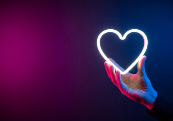 A hand holding up a large, bright white neon heart icon against a vibrant background, an impactful visual perfect for brand loyalty and customer satisfaction