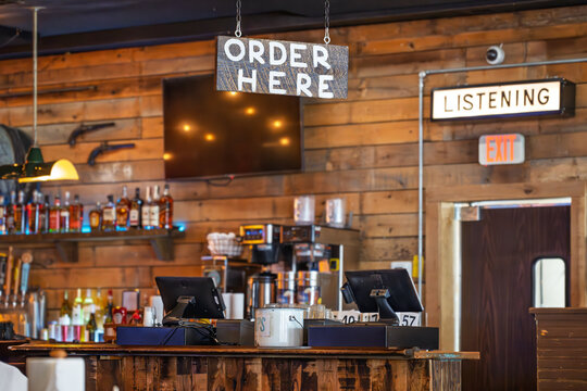An order here sign above a rustic old west style bar saloon with alcohol bottles blurred behind in the American small town of Leiper's Fork, Tennessee.