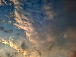 Fototapeta premium Golden clouds drifting across a darkening blue sky