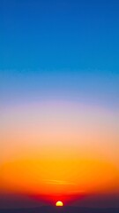 Fototapeta premium A breathtaking sunset paints the sky in vibrant hues of orange, pink, and purple, as the sun dips below the horizon, casting a warm glow over the landscape.
