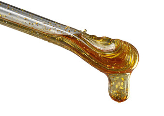 Golden liquid drips from a glass pipette