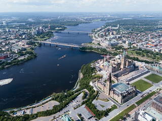 Naklejka premium Drone view of Canadian Parliament, Parliament Hill, House of Commons, and East Block in downtown of Ottawa and river in a sunny day, Canada.