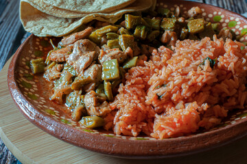 Mexican food, nopales with chicken, Mexican rice, and corn tortillas in a clay dish on a cutting board macro photography
