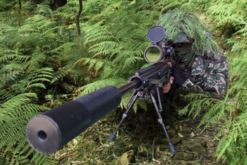 Military sniper wearing a camouflage waiting and looking through a rifle scope.