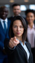 Fototapeta premium Businesswoman in suit pointing forward with colleagues behind her. 