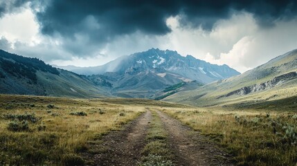 A dirt road leading through a grassy valley with a mountain in the distance, under a cloudy sky with dark clouds.