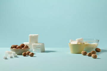 Overhead arrangement of shea butter pieces on wooden board, whole nuts and soft green sprigs adding...