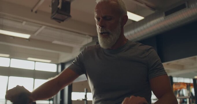 Fit mature man in sportswear looking
exhausted after working out on a
stationary bike at the gym