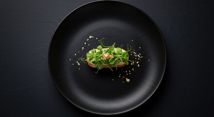 Canap&eacute; A small openfaced sandwich with sprouts and gold flakes on a black plate against a black background