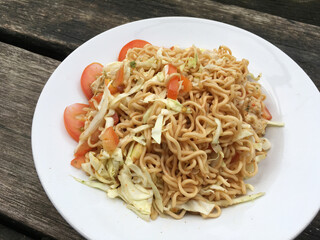 noodles with meat, vegetables and herbs on white plate