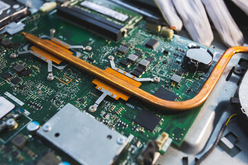 Close-up image of an all-in-one computer interior showing the motherboard, heat pipe cooling system, RAM slot, processor, and electronic components. Inside View of All-in-One Computer Motherboard