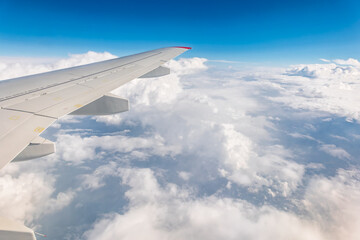 View from the airplane window at a beautiful cloudy sky and the airplane wing
